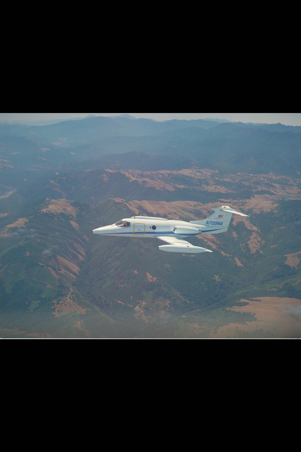 A real NASA Learjet 24B banking over the sunlit mountains of Central California in 1984